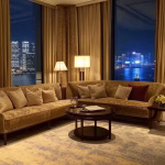 Hong Kong Peninsula Hotel suite interior at night, floor-to-ceiling windows with Victoria Harbour sk