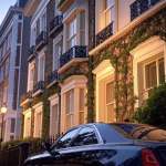 Elegant Georgian townhouse facade in Mayfair London during golden hour, ivy-covered walls, black iro