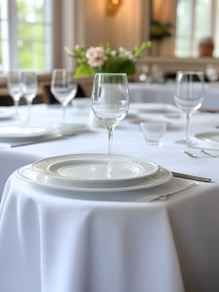 Elegant business lunch setup in a luxury restaurant, pristine white tablecloth with fine china and c