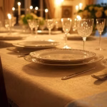 Intimate dinner party setup, beautifully set table with fine china and crystal glasses, soft candlel
