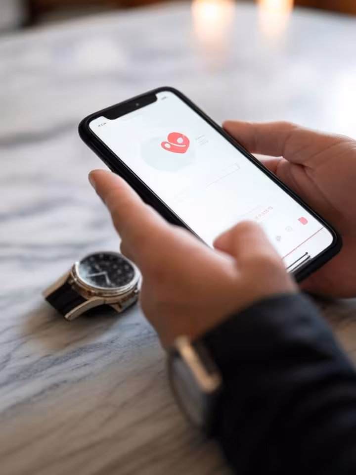 Close-up of hands holding smartphone showing exclusive dating app interface, luxury watch visible, m